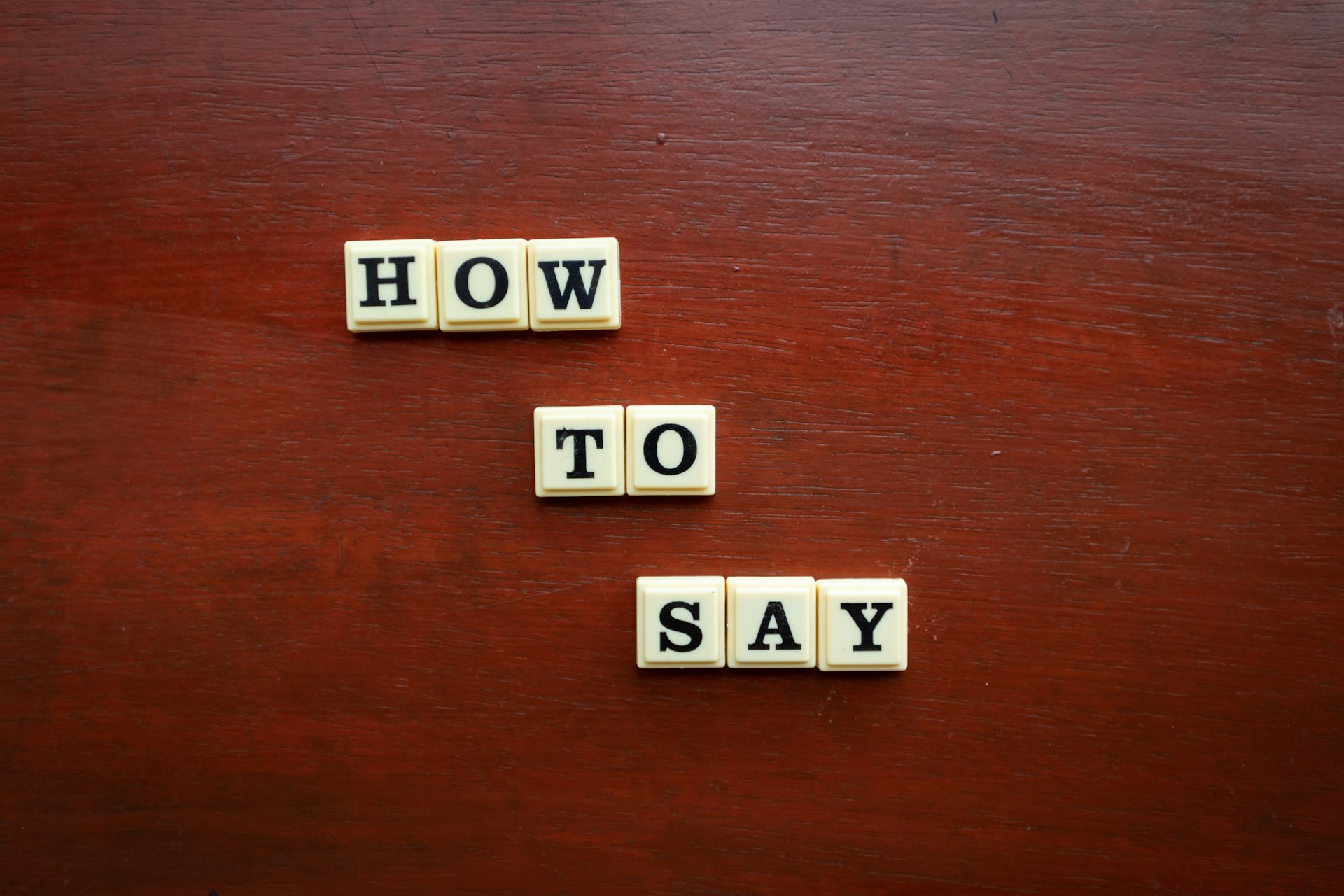 scrabble tiles spelling how to say on a wooden surface